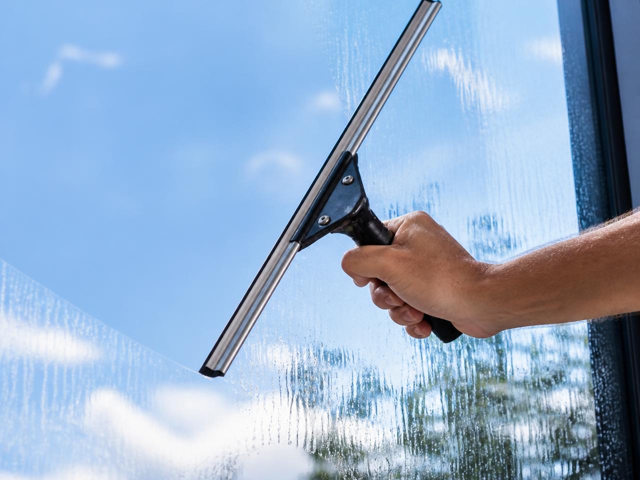 Squeegee clearing a window to reveal blue sky